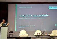 Cristy Rowley presenting at a podium beside a large screen showing the slide "Using AI for data analysis: Best practices and recommendations for nonprofit leaders" at the AccessTech 2026 Summit